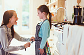 Mother tying apron on daughter in kitchen