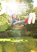 Girl swinging in sunny backyard