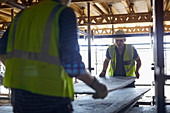 Construction workers lifting plyboard