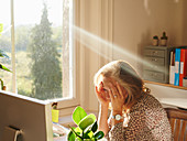 Stressed woman in sunny home office