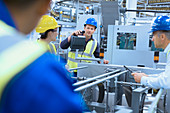 Workers talking at machinery in factory