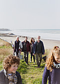 Family walking on grass beach path