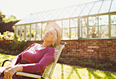 Senior woman relaxing outside greenhouse