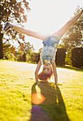 Girl doing handstand in sunny garden