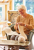 Smiling senior woman knitting scarf