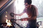 Blacksmith pouring liquid over tool