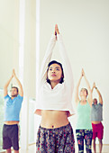Woman with arms raised in yoga class