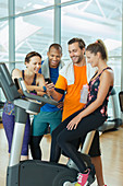 Friends using cell phone on exercise bike