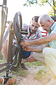 Father and adult son repairing bike chain
