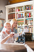 Senior couple drinking wine at typewriter