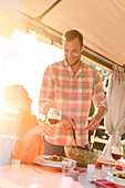 Man serving salad to wife drinking wine