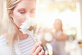 Woman smelling white gerber daisy