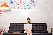 Businesswoman using laptop on sofa