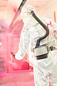 Worker painting steel red in factory