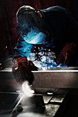 Welder using welding torch in factory