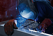 Welder using welding torch in factory