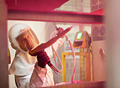 Worker painting steel red in factory