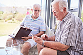 Senior men texting on patio