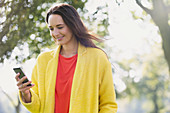 Smiling woman using cell phone in park