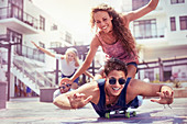 Playful young couple riding skateboard