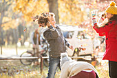 Boy throwing autumn leaves at girl