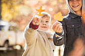 Boys holding golden autumn leaves