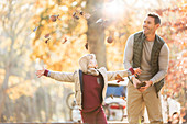 Father and son throwing autumn leaves