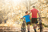 Father and son walking mountain bikes