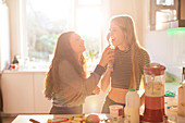 Girls playing with spoon in sunny kitchen