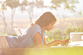 Woman laying using tablet on sunny patio