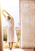 Woman in bathrobe stretching