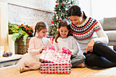 Mother and daughters opening gifts
