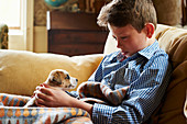 Boy holding puppy in lap on sofa