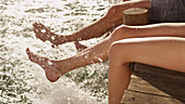 Young couple splashing bare feet in lake
