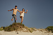 Young couple jumping on sandy beach