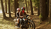 Young couple riding motorcycle in woods