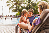 Mother and sons relaxing at poolside