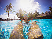 Boy in sunny tropical swimming pool