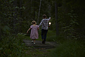 Brother and sister walking with lantern