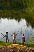 Girls fishing at sunny lakeside