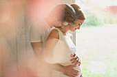 Pregnant couple hugging at window
