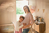 Pregnant mother and daughter in nursery