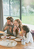 Family eating cupcakes at dining table