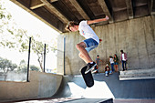 Boy flipping skateboard at skate park