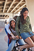 Playful teenage girls riding BMX bicycle