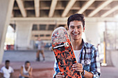 Portrait smiling boy holding skateboard