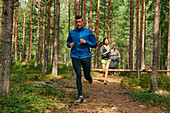 Runners running on trail in woods