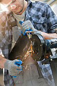 Metal worker using sander in workshop