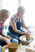 Senior couple using pottery wheels