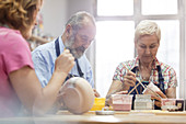 Senior couple painting pottery in studio